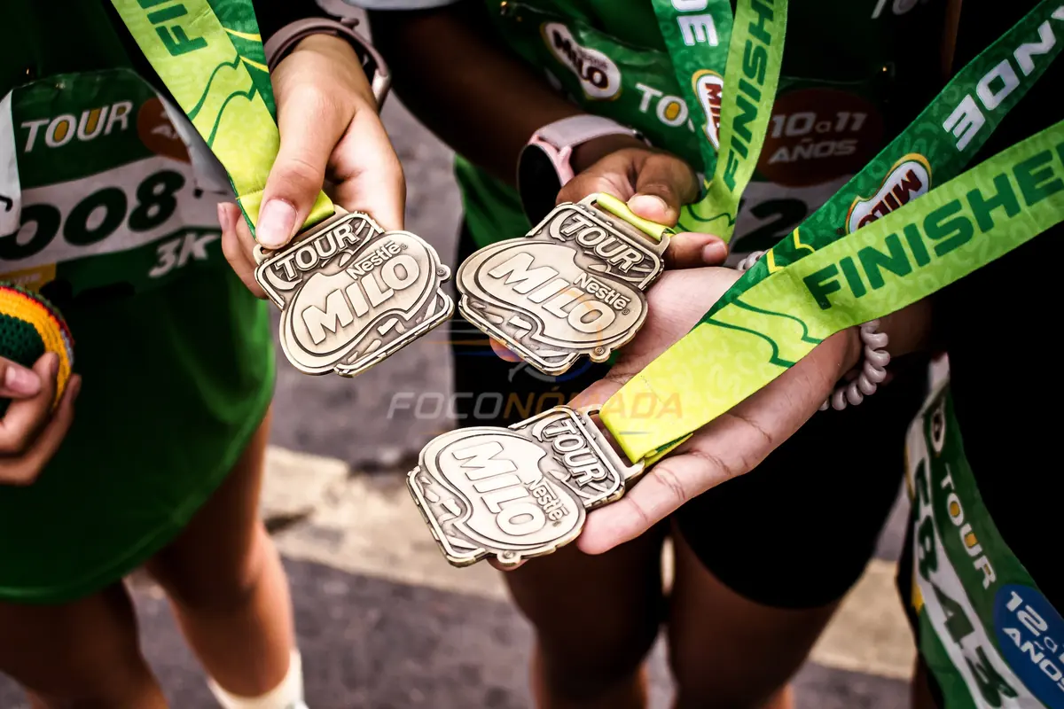 Medallas sostenidas por participantes de la Corrida Milo